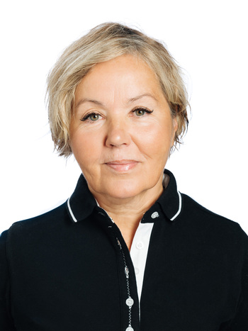 Porträtt av en kvinna med kort blont hår, klädd i en svart pikétröja, mot vit bakgrund.